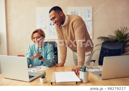 Cheerful Businesspeople Working Computer At Office. Colleagues Discussing Laptop Cheerful Businesspeople Working Computer At Office. Colleagues Discussing Laptop 98279227