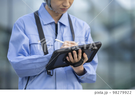 タブレットにペンで入力する作業服姿の男性の手元　撮影協力「LINK FOREST」 98279922