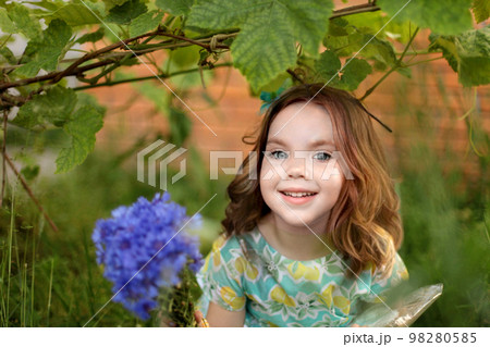 Cute little girl in autumn park holding bunch of yellow leaves. High quality photo 98280585