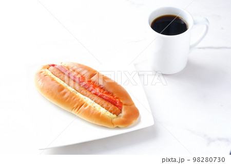 パリッとした食感のあらびきソーセージを挟んだホットドッグとコーヒーの軽食 98280730
