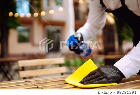 Disinfecting to prevent COVID-19. Waiter cleaning the table with Disinfectant Spray in a restaurant. Disinfecting to prevent COVID-19. Waiter cleaning the table with Disinfectant Spray in a restaurant. 98281591