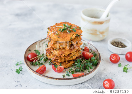 Crispy sweet potato fritters served with tomatoes and microgreens 98287159