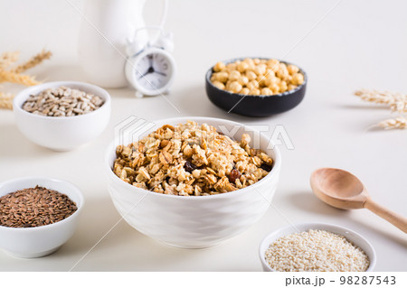 Baked granola in a bowl and different seeds in bowls on the table. Healthy breakfast. 98287543