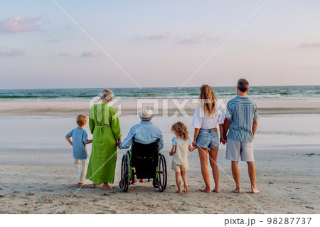 Rear view of three geneartions family with little kids enjoying time at sea in exotic country. 98287737