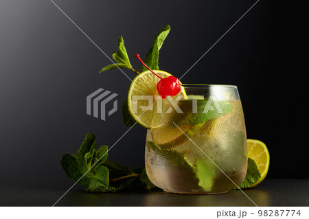 Cold refreshing drink with lime slices, mint, and cherry. 98287774