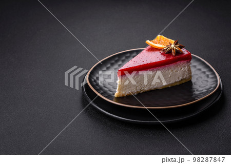 Delicious sweet cheesecake with raspberry jam on a black ceramic plate Delicious sweet cheesecake with raspberry jam on a black ceramic plate 98287847