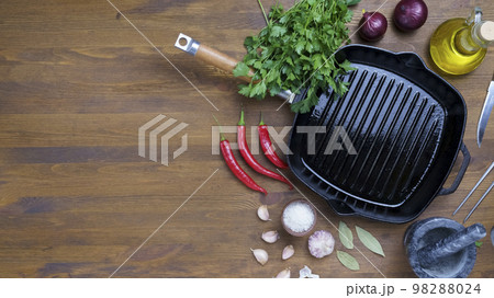 Black iron empty grill pan on wooden texture 98288024