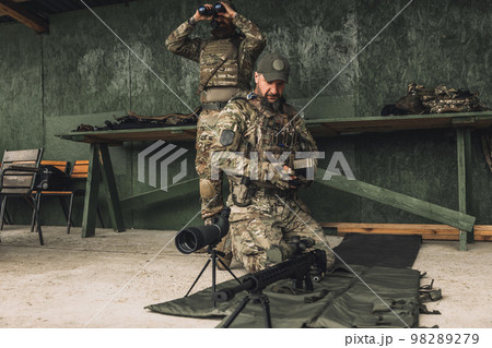 Serious soldier in camouflage with an optical rifle Serious soldier in camouflage with an optical rifle 98289279