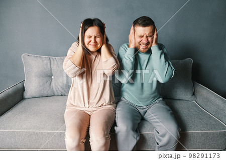 Stressed desperate couple closing ears with both hands irritated with loud annoying noise, having headache or migraine Stressed desperate couple closing ears with both hands irritated with loud annoying noise, having headache or migraine 98291173