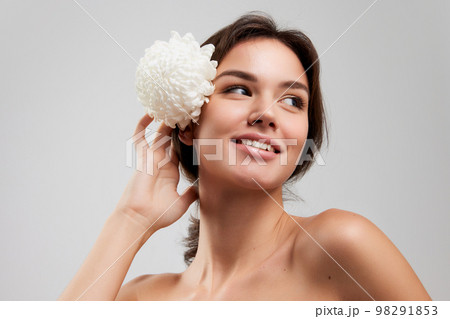 Close up beauty portrait of happy beautiful woman with bared shoulders applying face cosmetics products and looking with delighted facial expression isolated over light background Close up beauty portrait of happy beautiful woman with bared shoulders applying face cosmetics products and looking with delighted facial expression isolated over light background 98291853