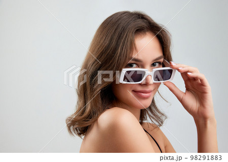 Portrait of young stylish beautiful girl in fashionable eyewear isolated over grey background. Concept of beauty, skin care, cosmetology, fashion, makeup 98291883