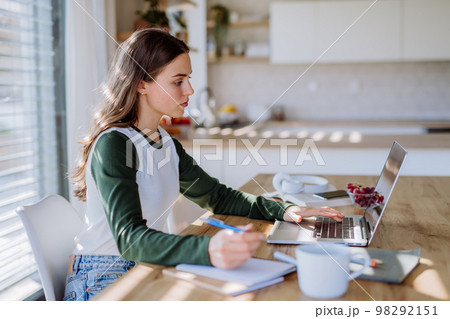 Young woman having distance education in her apartment. Young woman having distance education in her apartment. 98292151
