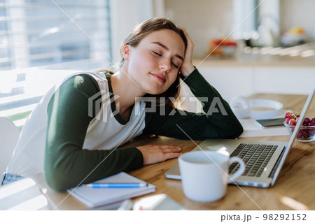 Young woman fall asleep at a table during learning. Young woman fall asleep at a table during learning. 98292152
