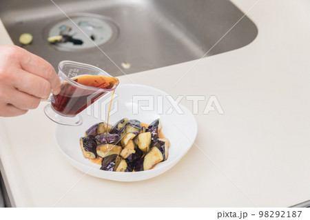 【茄子の揚げびたしを作る　炒めた茄子に麵つゆを入れる】 98292187