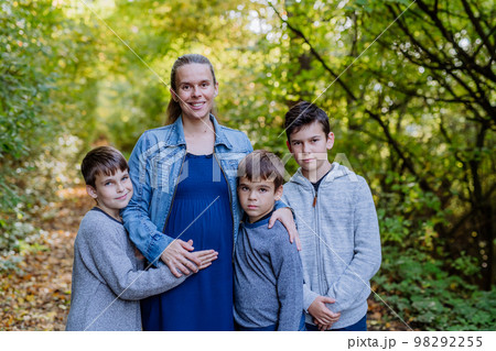 Portrait of pregnant mother and her three sons, outdoor in forest. 98292255