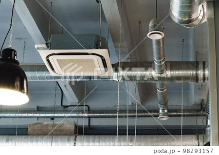 Silver ventilation pipes hanging from the ceiling inside the building 98293157