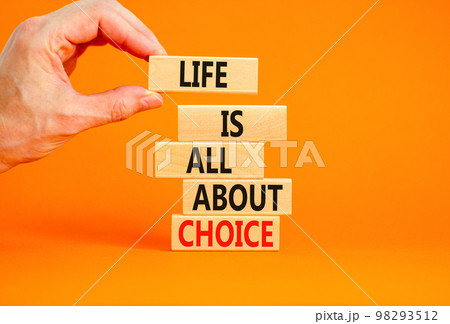 Choice and life symbol. Concept words Life is all about choice on wooden blocks. Beautiful orange table orange background. Businessman hand. Business choice and life concept. Copy space. 98293512