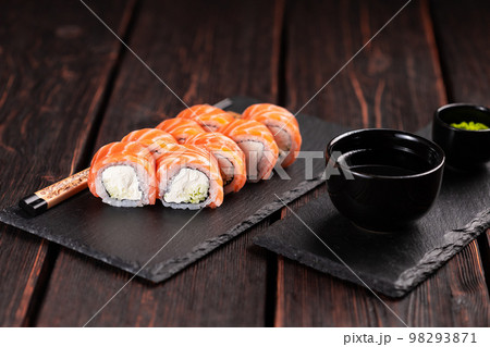 Sushi roll philadelphia with salmon and cucumber and cream cheese on black background. Sushi menu. Japanese food concept Sushi roll philadelphia with salmon and cucumber and cream cheese on black background. Sushi menu. Japanese food concept 98293871