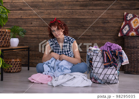 The tedious job of selecting shirts for washing. A girl with curly hair. The tedious job of selecting shirts for washing. A girl with curly hair. 98295035