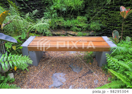 Chairs made of mortar destroyed like wood in a public garden. The surrounding area is full of small trees. make the atmosphere relax. 98295304