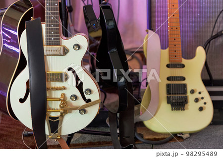 Close up of Electric and acoustic guitars on stands before a stage show Close up of Electric and acoustic guitars on stands before a stage show 98295489