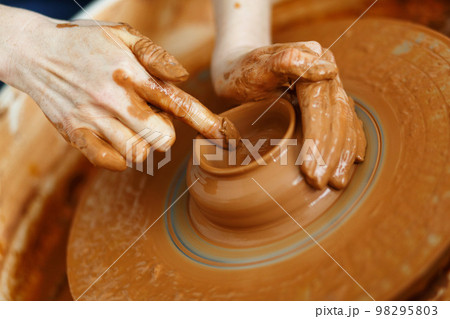 Potter creates a pitcher on a pottery wheel 98295803