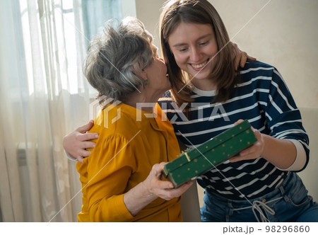 Grandmother and daughter make gifts to each other. Grandmother and daughter make gifts to each other. 98296860