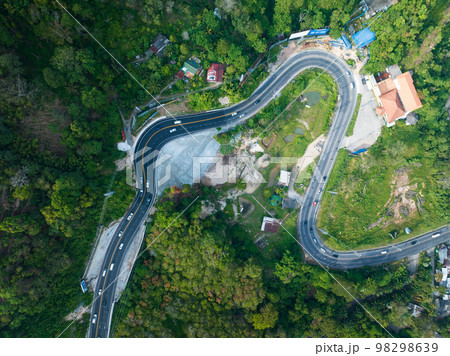 Aerial view top down drone shot above the winding mountain road between the trees rainforest,Phuket Thailand,in summer season weather, Car driving through the curve road Aerial view top down drone shot above the winding mountain road between the trees rainforest,Phuket Thailand,in summer season weather, Car driving through the curve road 98298639