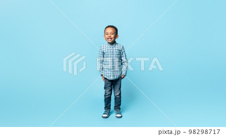 Happy childhood. Full length portrait of adorable little african american boy smiling to camera, blue background Happy childhood. Full length portrait of adorable little african american boy smiling to camera, blue background 98298717