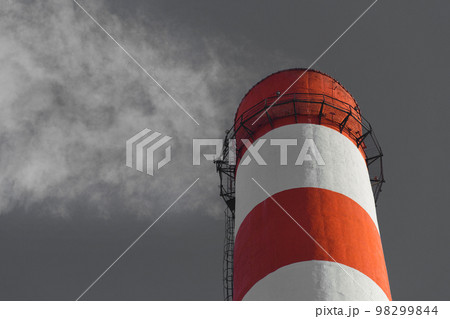Pollution of the environment, ecology and air. Withdrawal of combustion products of soot, smoke and gases from the pipe of an industrial plant into the atmosphere against the background of a gray sky Pollution of the environment, ecology and air. Withdrawal of combustion products of soot, smoke and gases from the pipe of an industrial plant into the atmosphere against the background of a gray sky 98299844