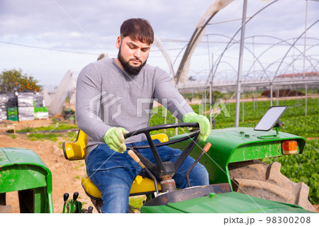 Guy driving farm tractor Guy driving farm tractor 98300208