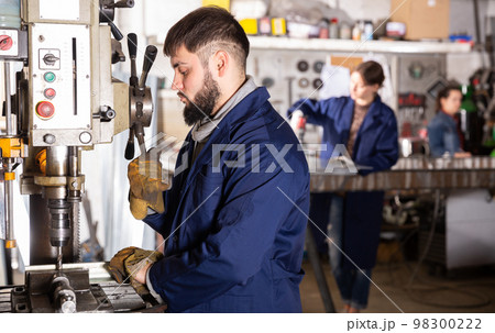 Portrait of man working with drilling machine on metal plate Portrait of man working with drilling machine on metal plate 98300222