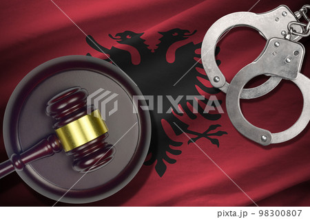 Albania flag with judge mallet and handcuffs in dark room. Concept of criminal and punishment, background for judgement topics Albania flag with judge mallet and handcuffs in dark room. Concept of criminal and punishment, background for judgement topics 98300807