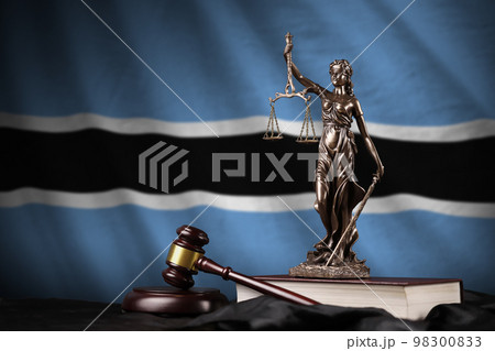 Botswana flag with statue of lady justice, constitution and judge hammer on black drapery. Concept of judgement and guilt 98300833