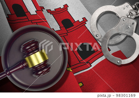 Giblartar flag with judge mallet and handcuffs in dark room. Concept of criminal and punishment, background for judgement topics 98301169
