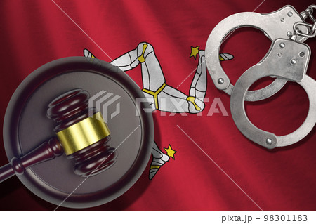 Isle of Man flag with judge mallet and handcuffs in dark room. Concept of criminal and punishment, background for judgement topics 98301183