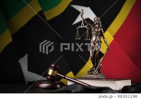 Saint Kitts and Nevis flag with statue of lady justice, constitution and judge hammer on black drapery. Concept of judgement and guilt 98301196
