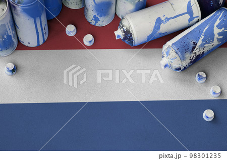 Netherlands flag and few used aerosol spray cans for graffiti painting. Street art culture concept 98301235