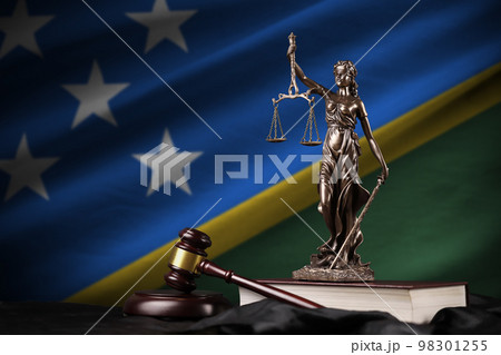 Solomon Islands flag with statue of lady justice, constitution and judge hammer on black drapery. Concept of judgement and guilt Solomon Islands flag with statue of lady justice, constitution and judge hammer on black drapery. Concept of judgement and guilt 98301255