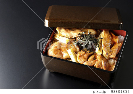 タレがたっぷりかかった焼き長葱と焼き鳥重を黒背景で撮影 98301352