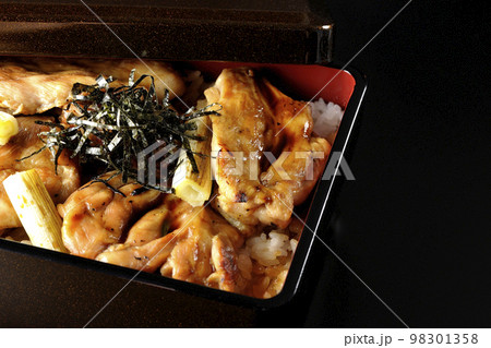 タレがたっぷりかかった焼き長葱と焼き鳥重を黒背景で撮影 タレがたっぷりかかった焼き長葱と焼き鳥重を黒背景で撮影 98301358