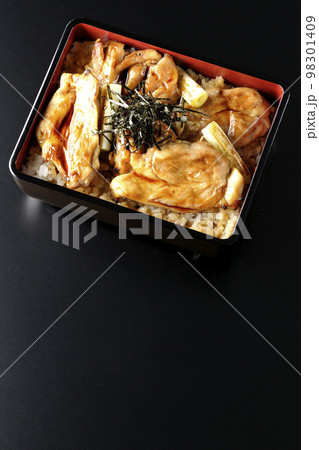 タレがたっぷりかかった焼き長葱と焼き鳥重を黒背景で俯瞰撮影 98301409