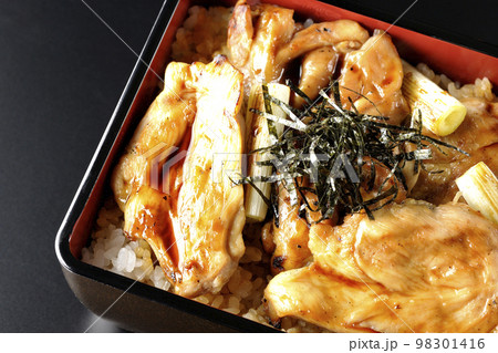 タレがたっぷりかかった焼き長葱と焼き鳥重を黒背景で俯瞰撮影 98301416