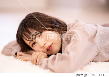 カーペットに寝転んでくつろぐ若い女性 98301419