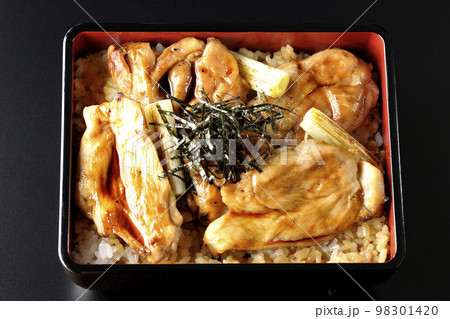 タレがたっぷりかかった焼き長葱と焼き鳥重を黒背景で俯瞰撮影 タレがたっぷりかかった焼き長葱と焼き鳥重を黒背景で俯瞰撮影 98301420