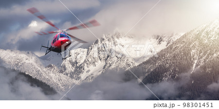 Helicopter flying over the Rocky Mountains during a cloudy winter day. 98301451