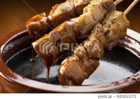 鶏のモモ肉の串焼きをタレ壺の中の焼き鳥のタレに漬ける 鶏のモモ肉の串焼きをタレ壺の中の焼き鳥のタレに漬ける 98302273