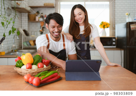 Portrait of young asian couple making salad together at home. cooking food and Lifestyle moment and healthy Portrait of young asian couple making salad together at home. cooking food and Lifestyle moment and healthy 98303809
