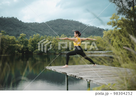 Woman practicing yoga on the bridge at lake.Yoga and healthy lifestyle concept. Woman practicing yoga on the bridge at lake.Yoga and healthy lifestyle concept. 98304252