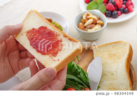 朝食のトーストにジャムを塗る人 98304349